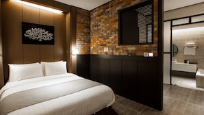 Ein modernes Hotelzimmer mit einem großen Bett, einer Ziegelwand, einem Wandbild und einem durchgegangenen Tür angedeuteten Badezimmer.