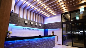 Ein Hotelrezeptionstresen mit modernem Design, mit einer Steinfront, einer Uhr und einem Schild mit der Aufschrift "CS PREMIER HOTEL".