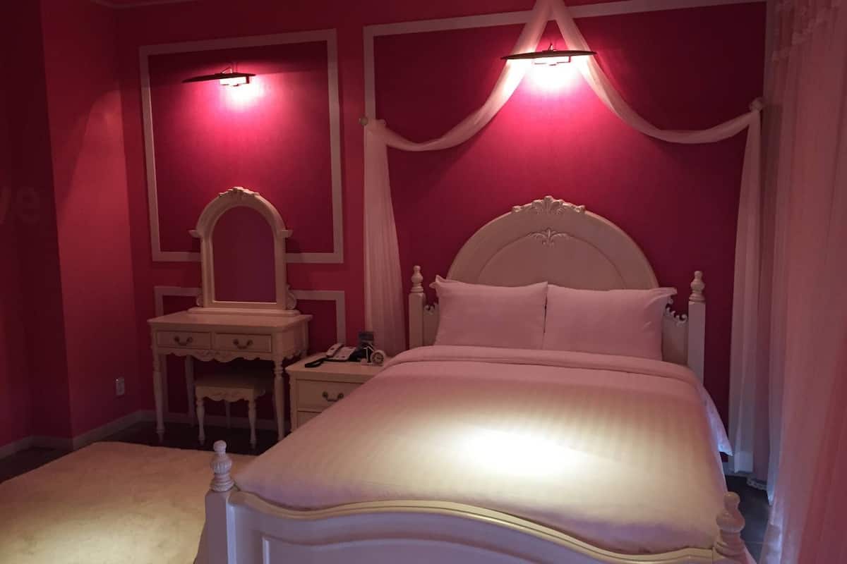 Ein Schlafzimmer mit einem Bett, einem Nachttisch, einer Kommode und einem Spiegel.