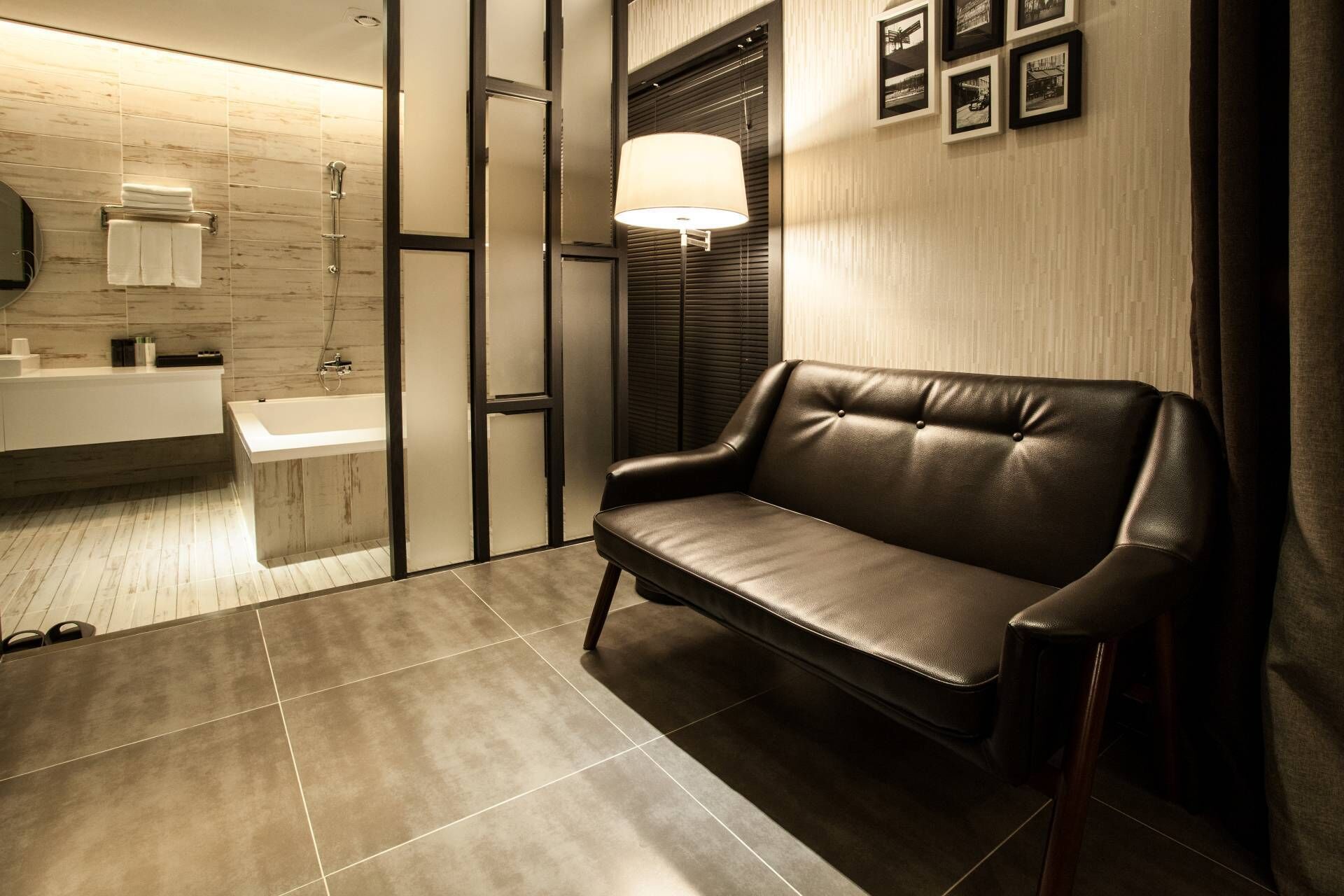 A modern bathroom with a black leather bench, a white sink, and a large mirror.