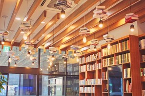 A library interior with bookshelves, hanging light fixtures, and a television. - Cs Premier Hotel (Anyang)