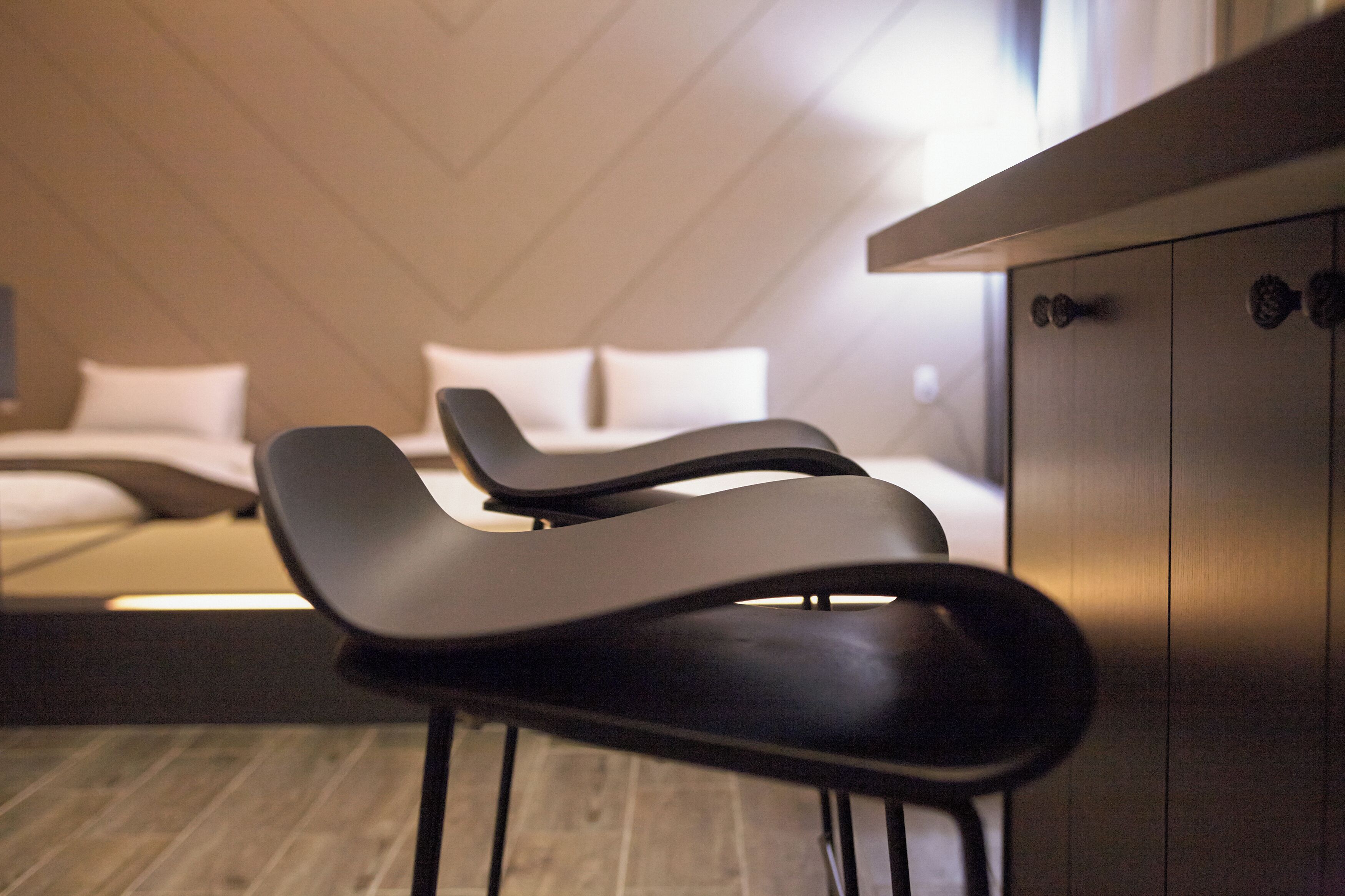 A modern bedroom with a bed, a wooden ceiling, and a nightstand with a lamp.