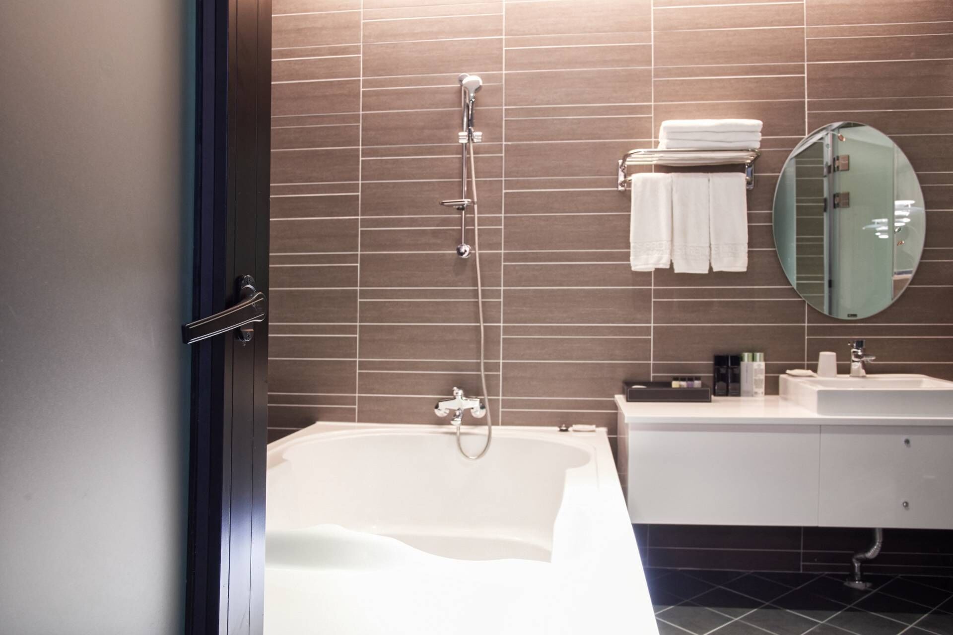 A modern bathroom with a bathtub, a sink, a mirror, and neatly arranged towels.
