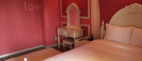 A bedroom with a bed, a vanity with a mirror, a nightstand, and a wall with the text 'hello, love'.