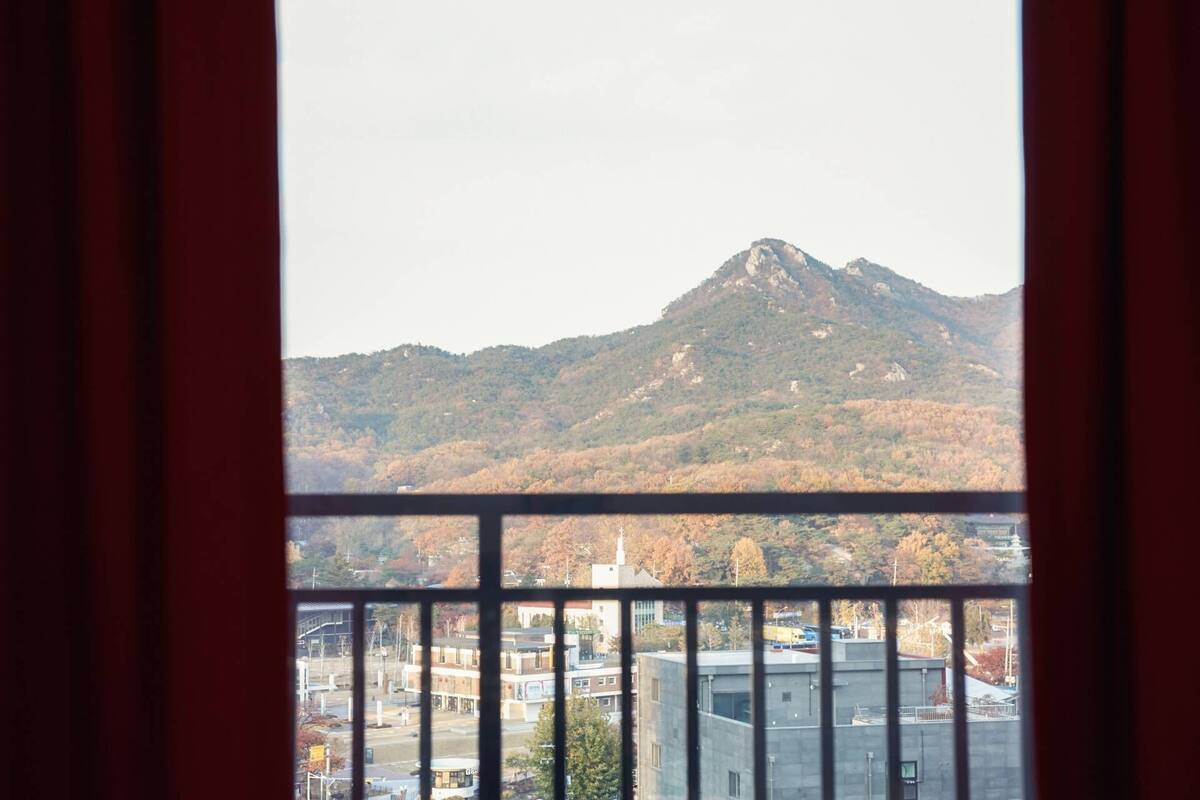 Blick auf einen Berg durch ein Fenster mit Metallgitter.