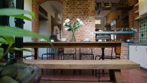 Una cocina rústica con paredes de ladrillo visto, una mesa de madera y un jarrón con flores blancas.