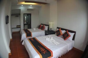 A hotel room with two beds, each with a white bedspread and orange trim. There is a nightstand with a lamp between the beds. - Sea Sun Homestay (Da Nang)