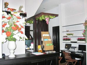 A reception area with a desk, computer, chair, and shelves with decorative items. - Sea Sun Homestay (Da Nang)
