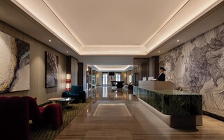 Un moderno vestíbulo de hotel con mostrador de recepción, zona de estar y obras de arte en las paredes.