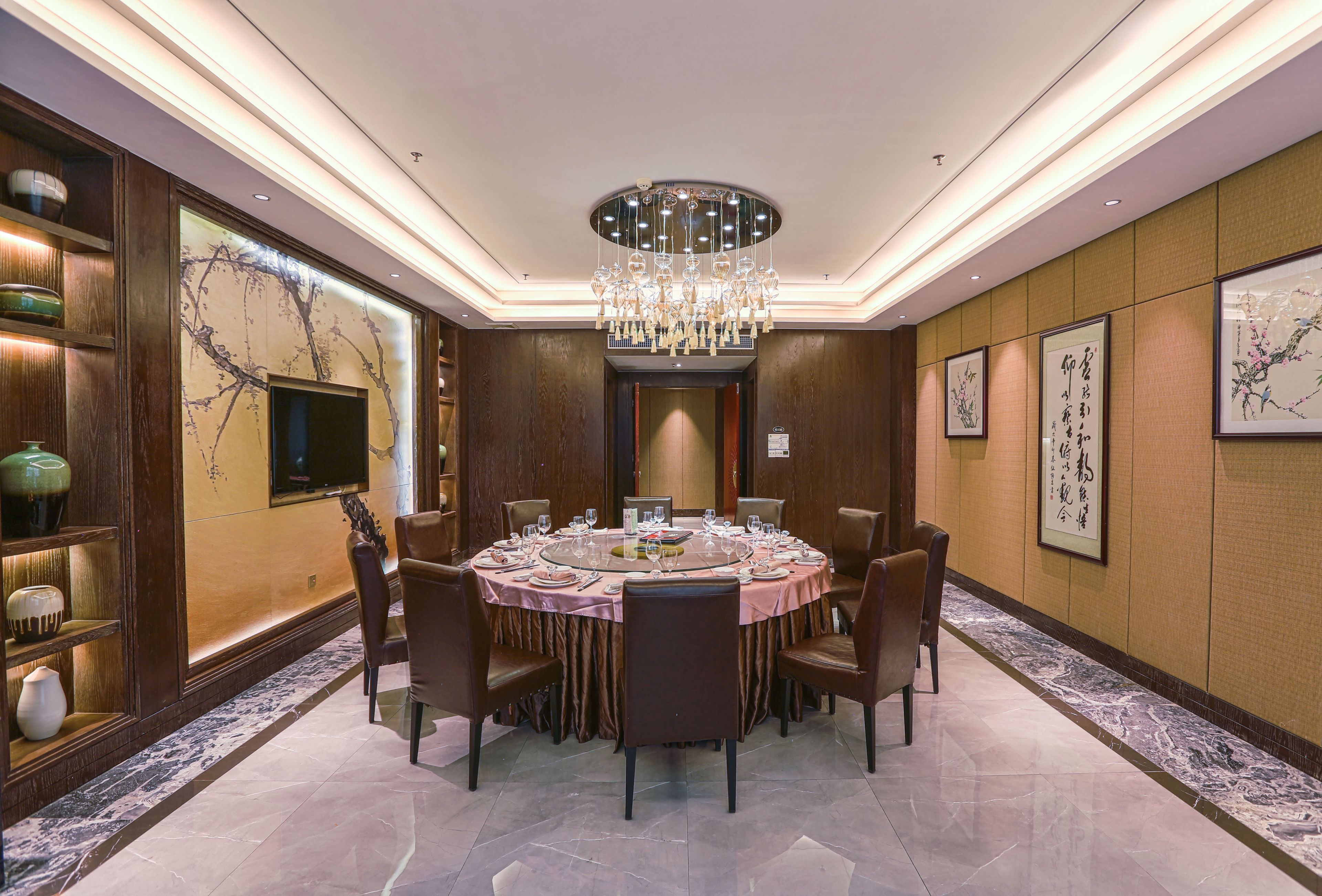 A round dining table with chairs, a chandelier, and artwork on the walls.