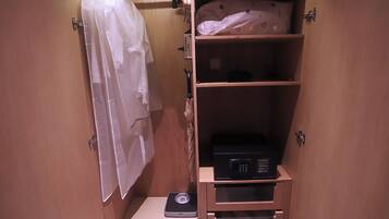 A small bathroom with a scale, a shelf with a pillow, and a towel hanging on a hook.
