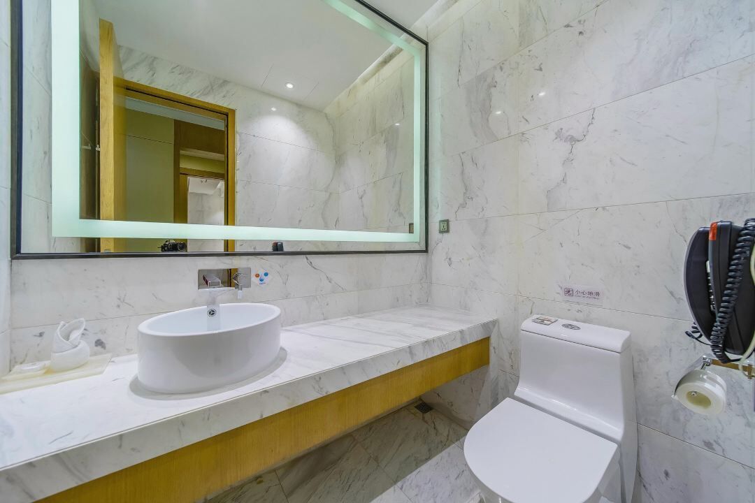 A modern bathroom with a white sink, a large mirror, and a toilet.