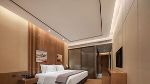 A modern hotel room with a large bed, bedside tables, a TV, and a sliding door leading to a bathroom. - Palm Spring Hotel (Zhuhai)