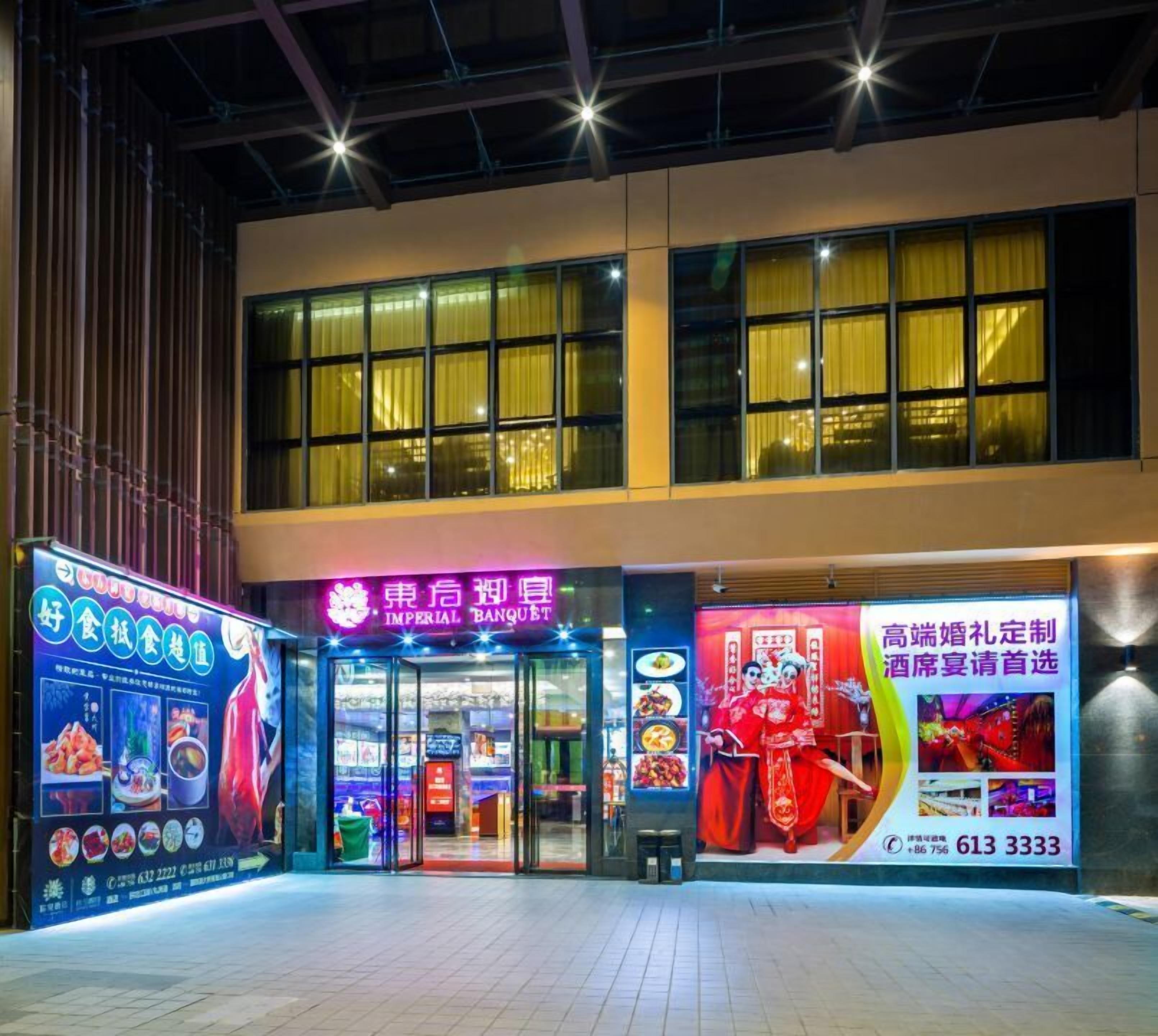 Een gebouw met grote ramen en een neonreclame voor een restaurant.