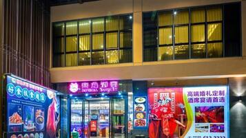 A building with large windows and a neon sign for a restaurant.