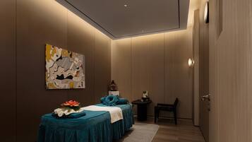 A modern spa room with a massage table, a small massage chair, and a wall-mounted massage table.