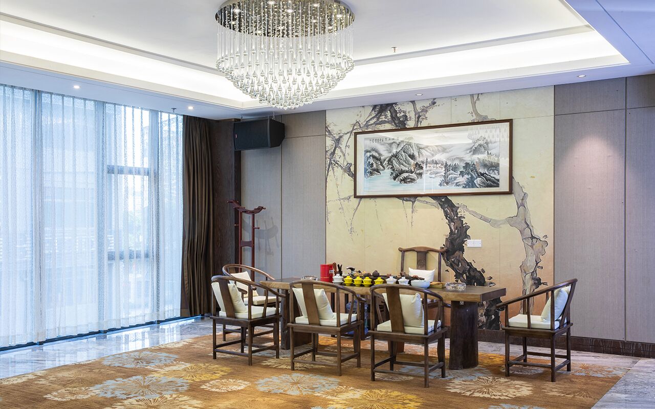 A dining area with a chandelier, a table with chairs, a painting on the wall, and a large window with curtains.