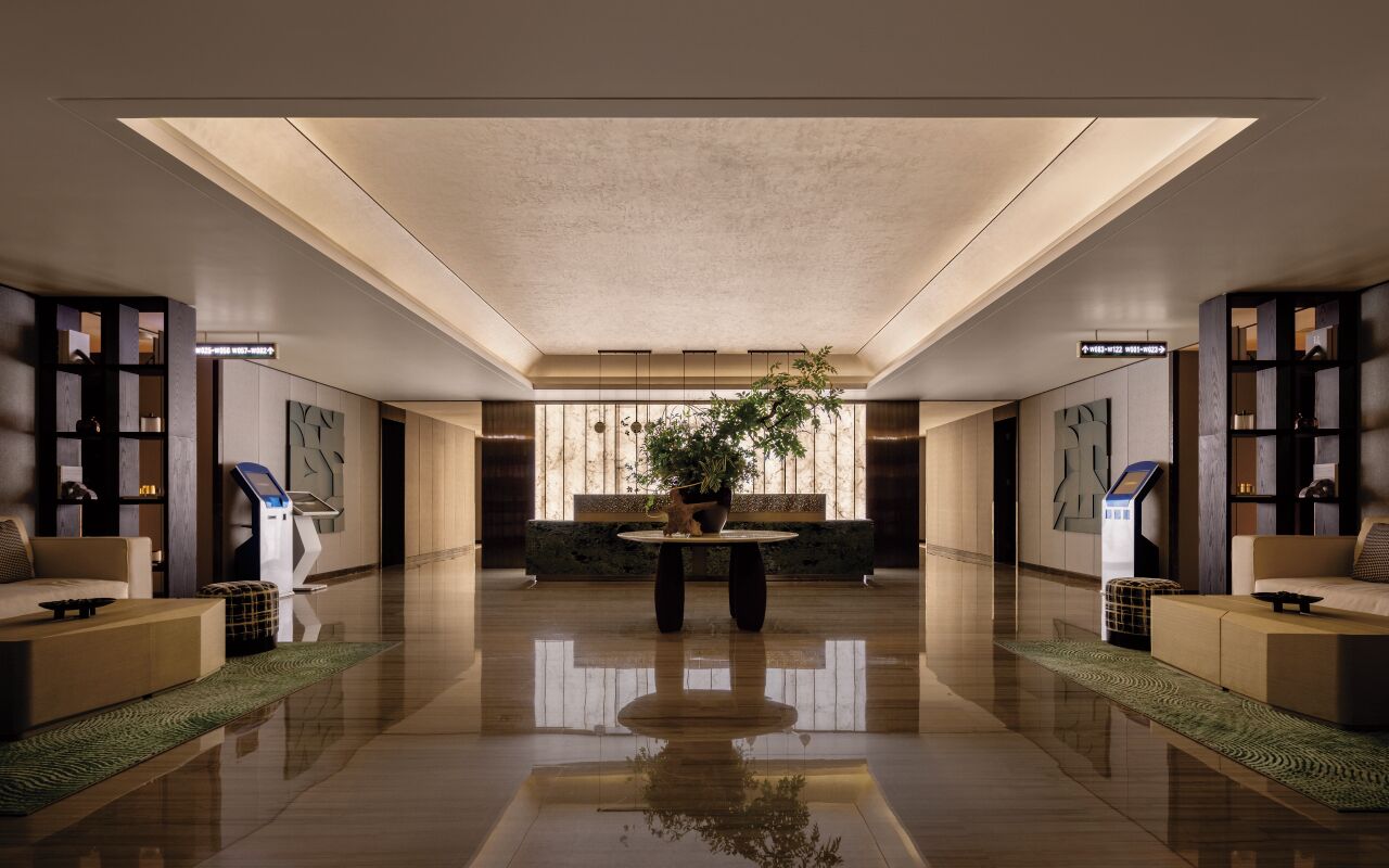 A spacious lobby with a central seating area, a large window with natural light, and modern furnishings.