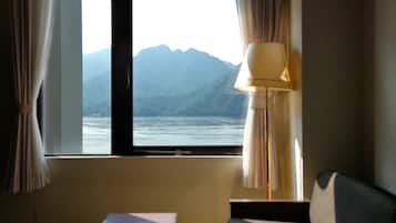 Habitación con vistas a una montaña y al agua a través de una ventana, una lámpara y un sofá.