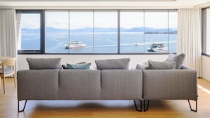 A modern living room with a large window overlooking a body of water and boats.