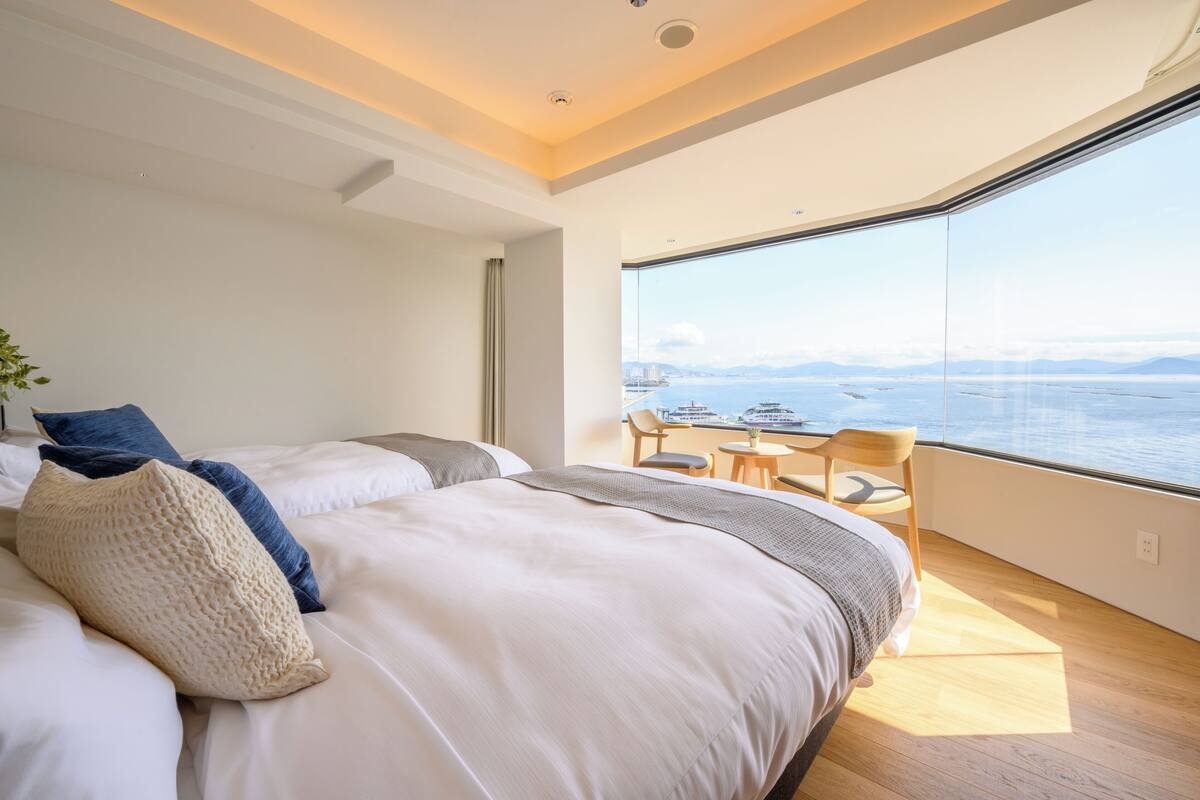 Ett modernt hotellrum med en stor säng, ett litet bord och utsikt över havet.