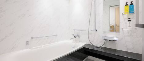 Une salle de bain moderne avec une baignoire blanche, un plan de toilette noir et un miroir au-dessus du lavabo.