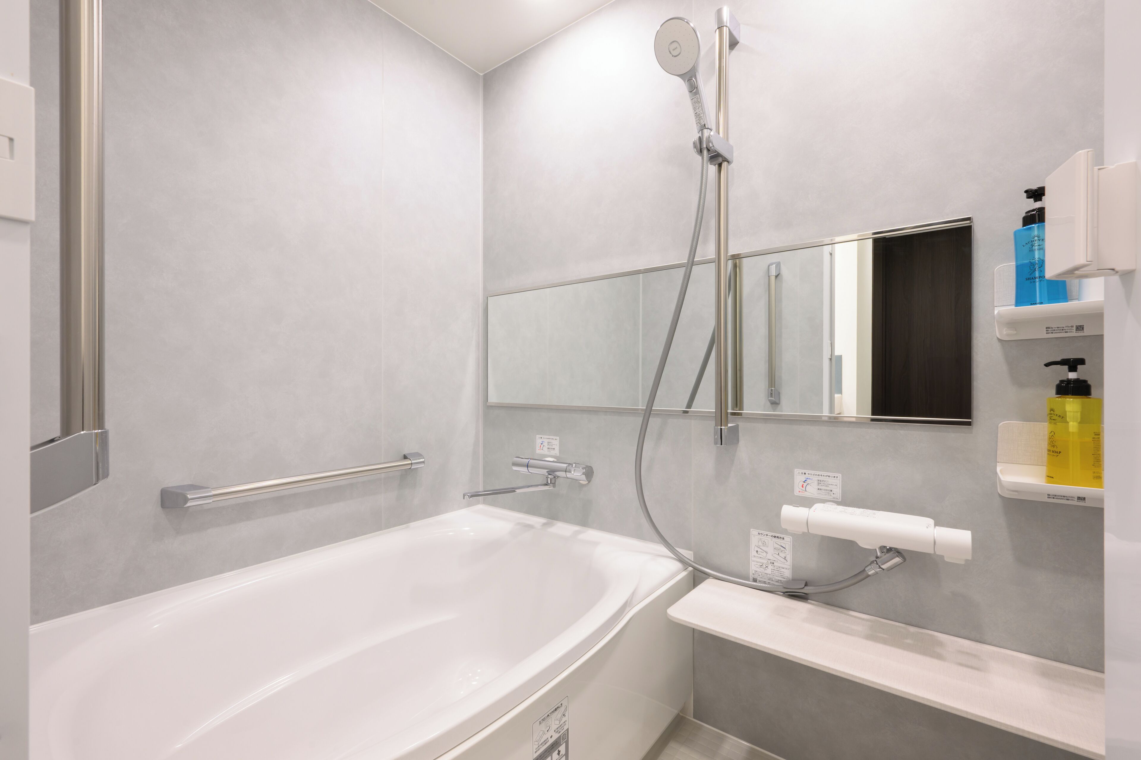 Un baño moderno con bañera, ducha con cabezal de ducha manual, toallero y espejo.