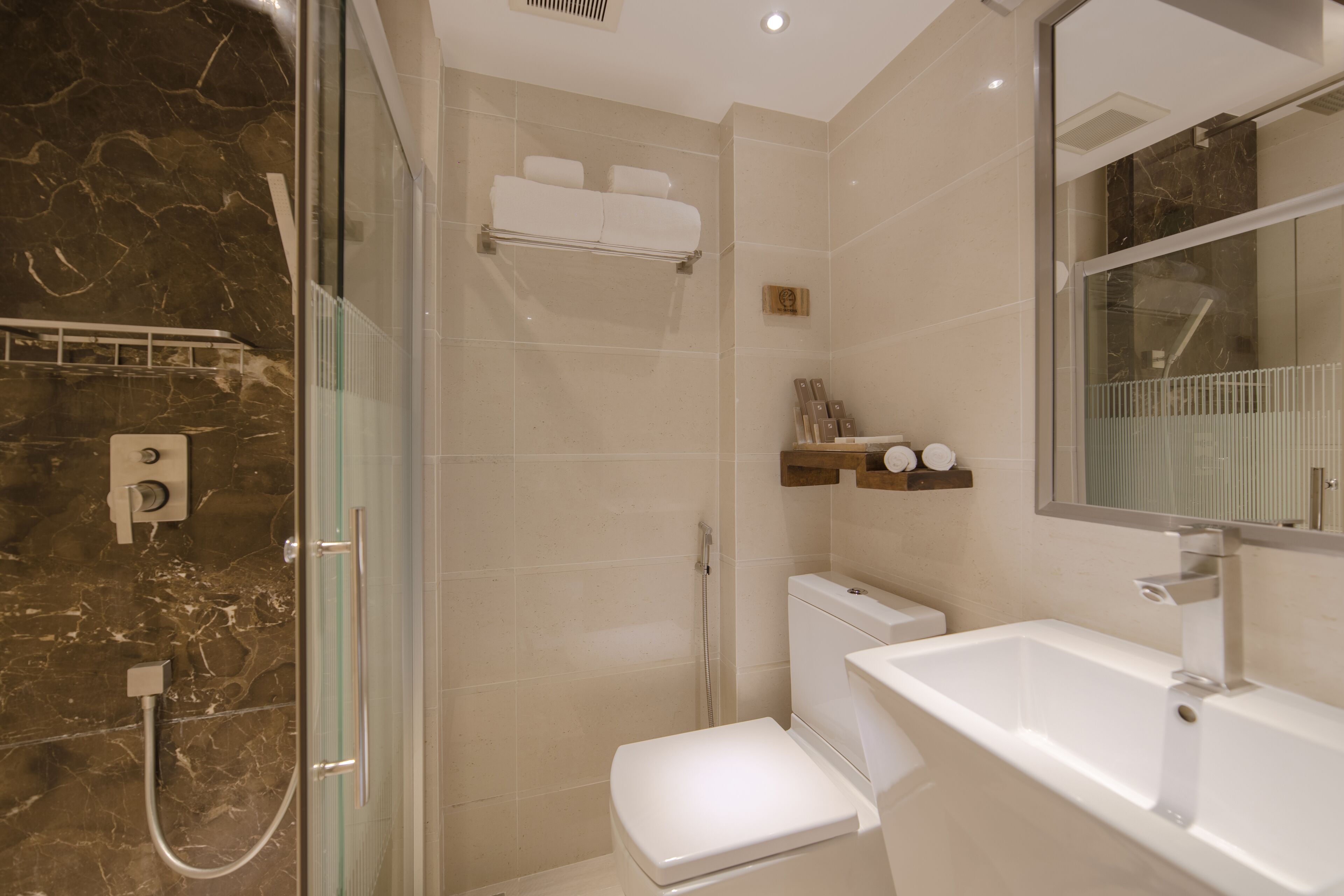 Une salle de bain moderne avec une douche à parois de verre, des toilettes blanches et un lavabo avec un miroir.