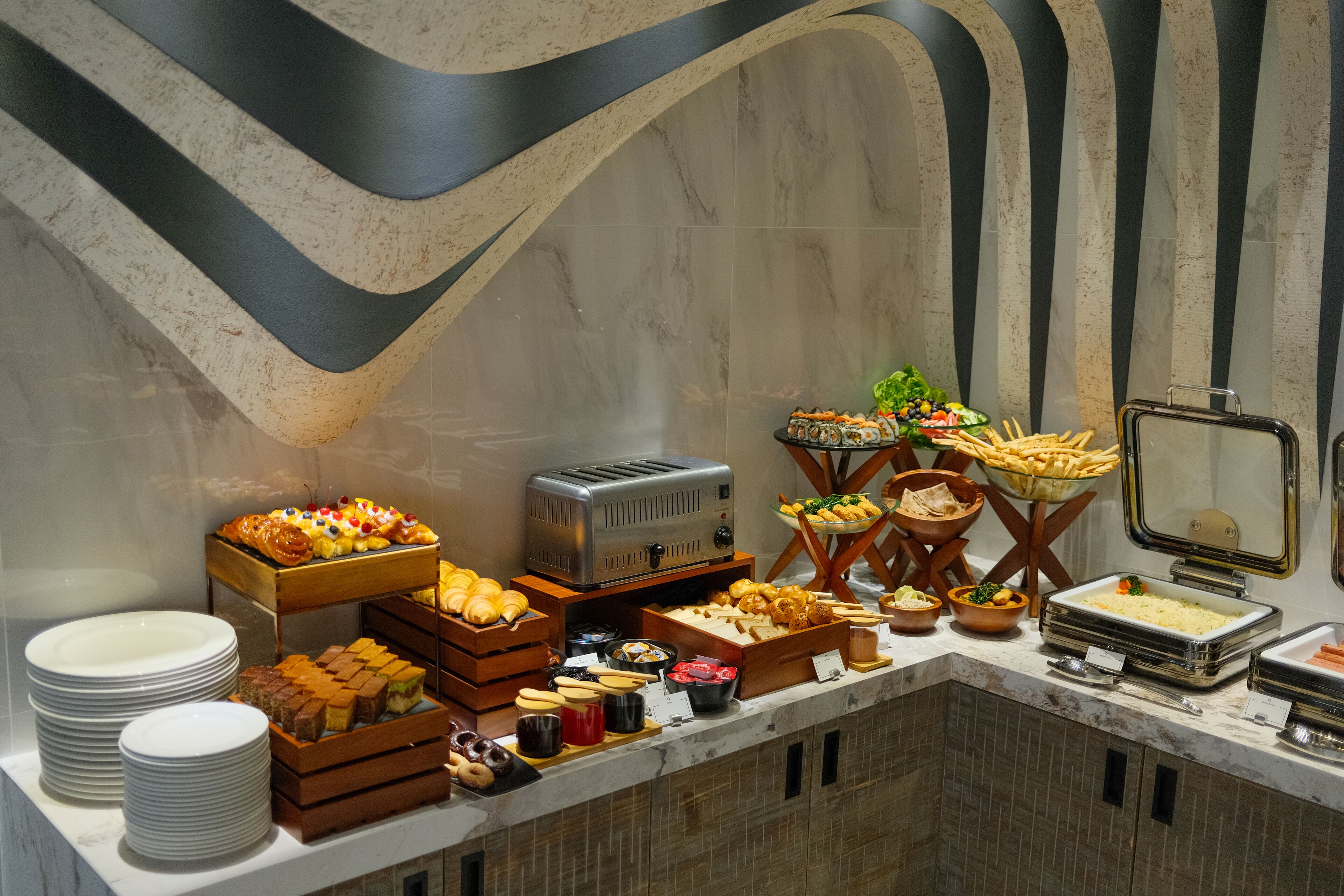A buffet with various food items, including pastries, fruits, and a toaster.