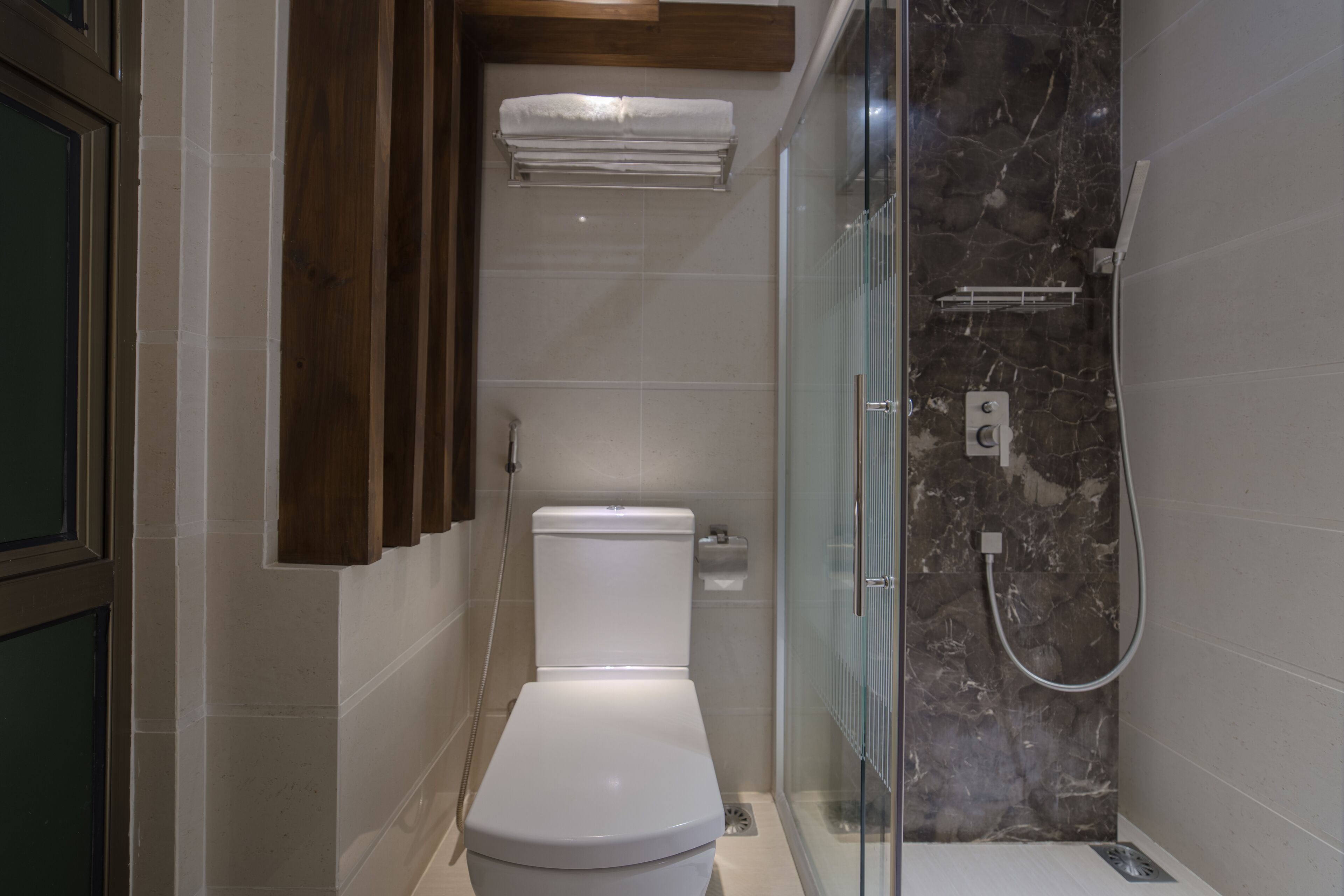 Un baño moderno con inodoro, ducha con mampara de vidrio y barra para toallas.