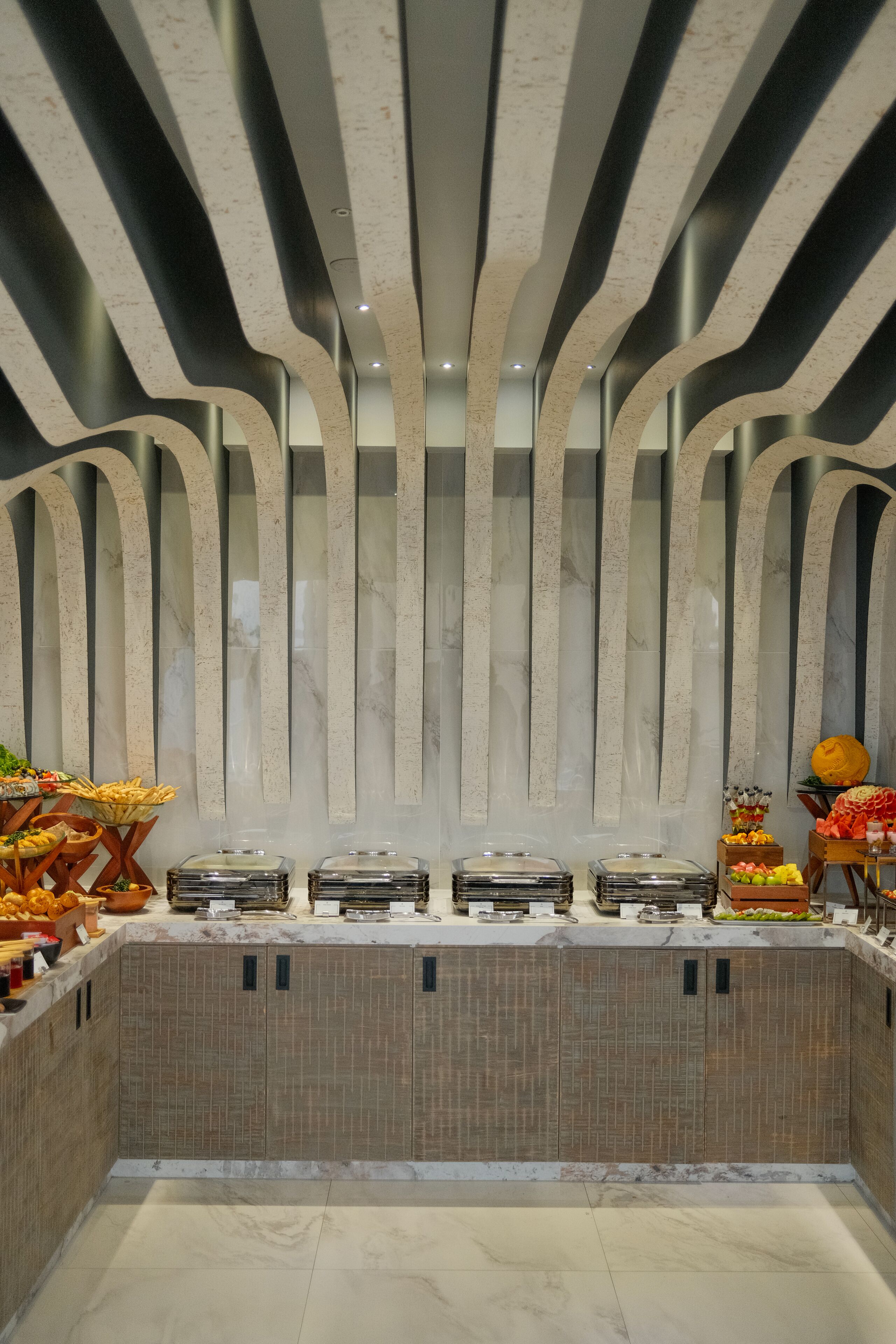 Ein reichhaltiges Buffet mit verschiedenen Speisen und einem modernen Deckenstil.