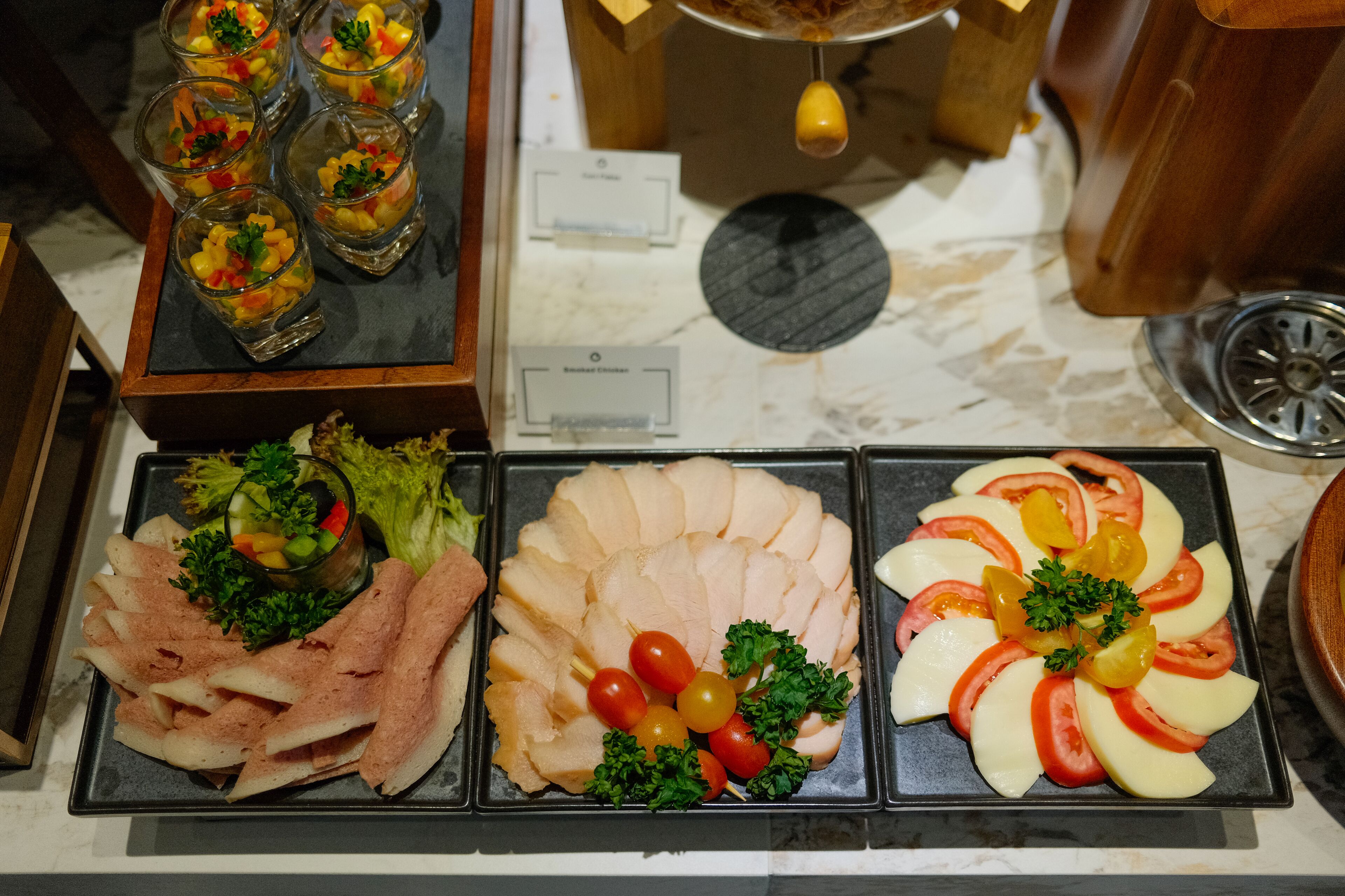 A buffet with various food items including sliced meats, cheeses, and fresh vegetables.