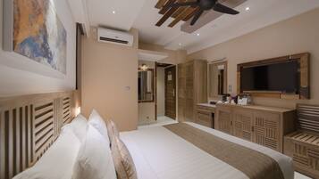 Habitación de hotel con cama, ventilador de techo, aire acondicionado, televisor y armario de madera.