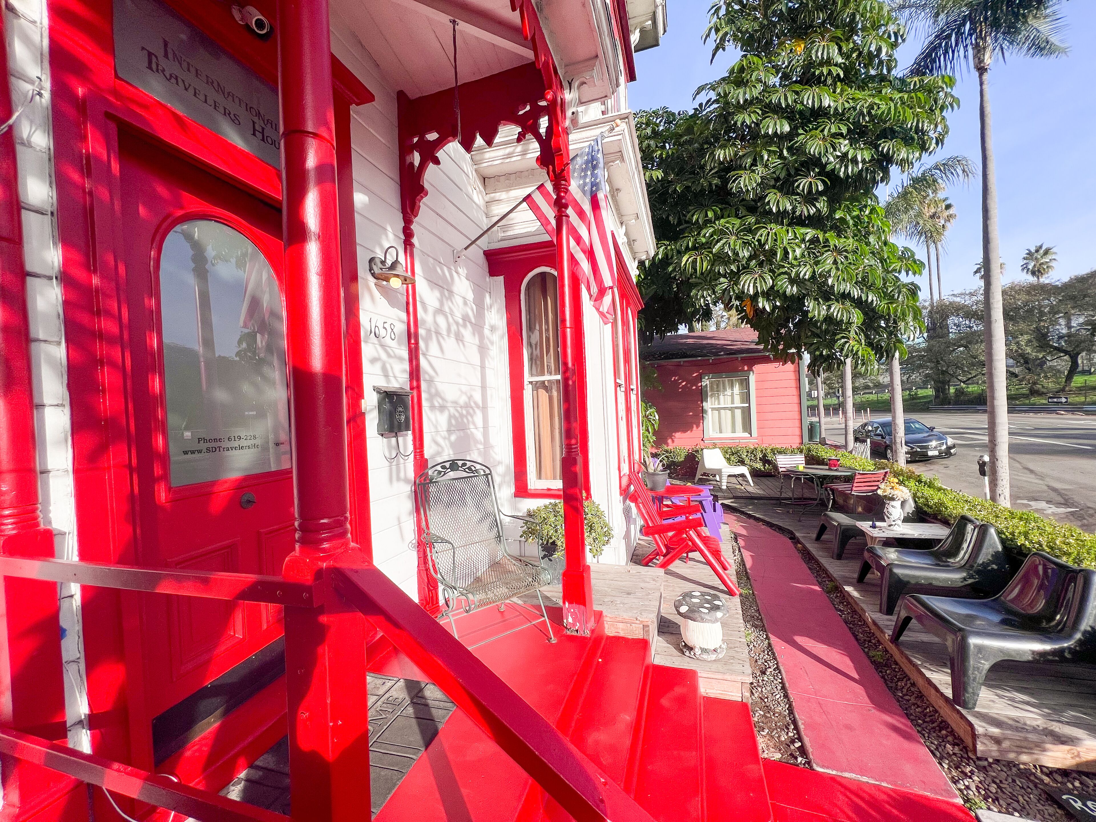 Un edificio rojo con una puerta blanca, un buzón y una pequeña mesa con sillas afuera.