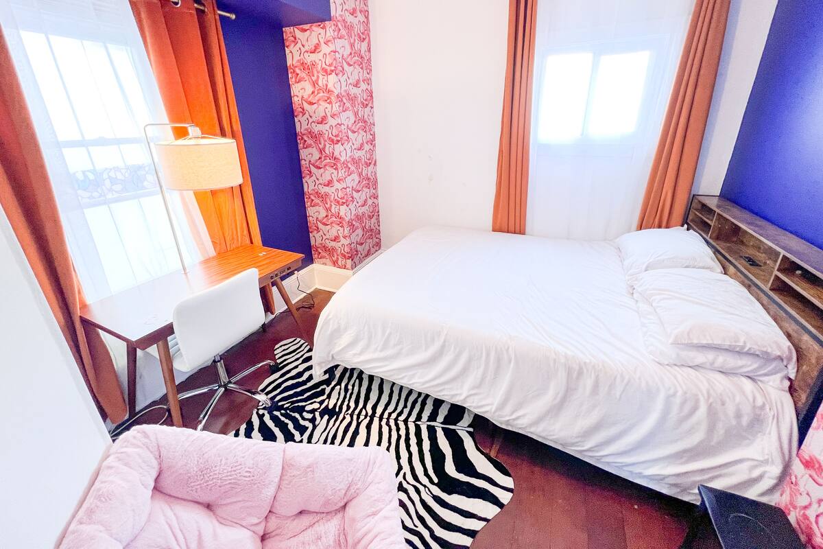 Ein Hotelzimmer mit einem Bett, einem Schreibtisch, einem Stuhl und einem Teppich mit ZEBRA-MUSTER.
