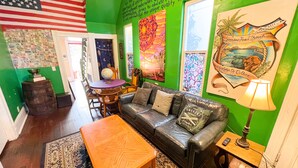 A room with a green wall, a leather couch, a wooden table, and a globe on a table.