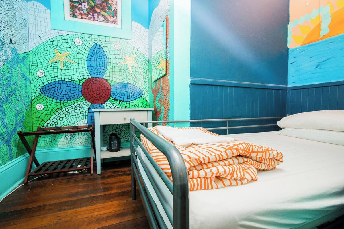 Ein Schlafzimmer mit einem Bett, einem Nachttisch und einer Wand mit Mosaikmuster.