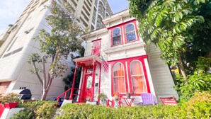 A Victorian-style building with a red and white facade, a front porch, and a staircase leading to the entrance.
