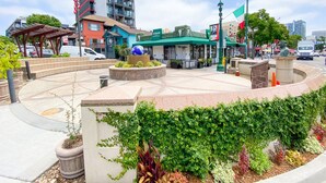 A public square with a circular seating area, a globe sculpture, and a restaurant with a green awning.
