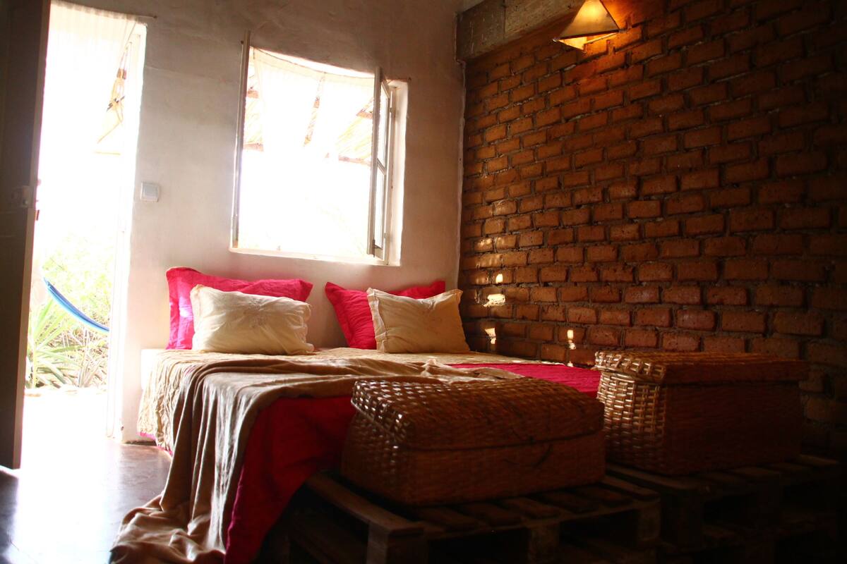 A room with a bed, a brick wall, and a window.