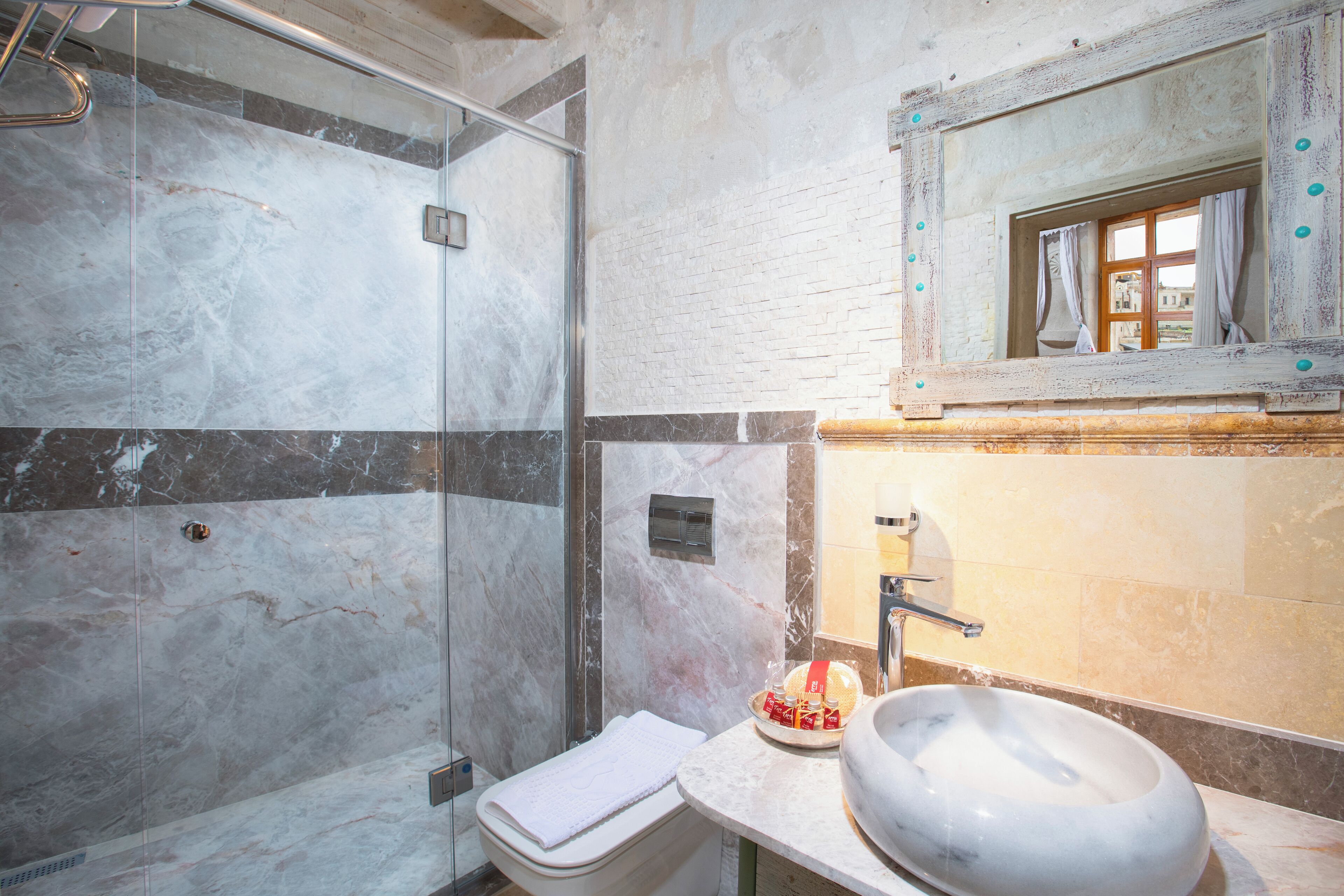 A bathroom with a glass shower enclosure, a white sink, and a mirror above the sink.