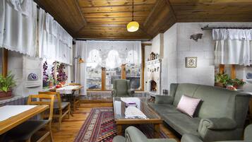 Un salón acogedor con muebles de madera, un sofá verde y una alfombra estampada.