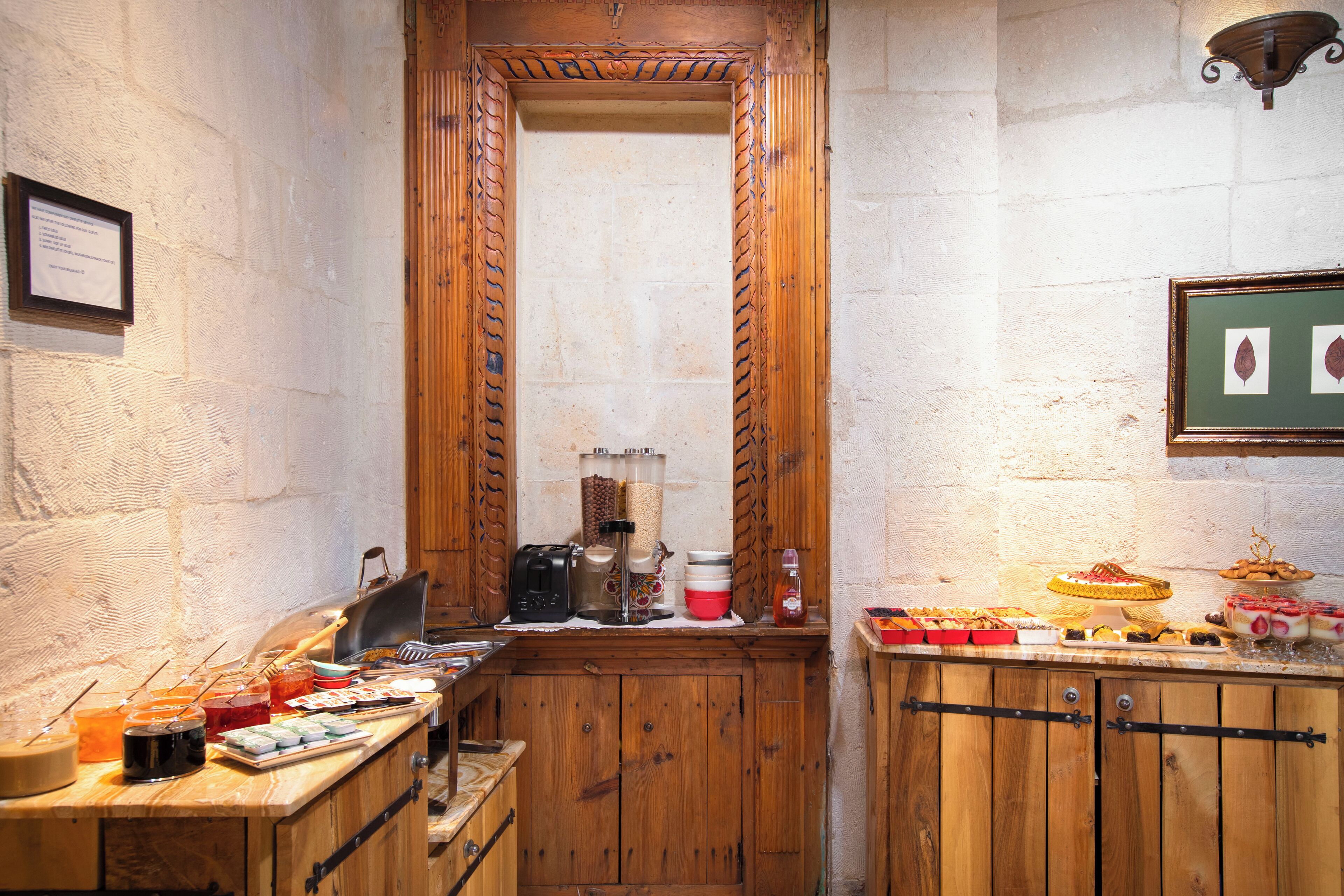 A narrow kitchen with wooden cabinets, a wooden-framed mirror, and a variety of food items on the counter.