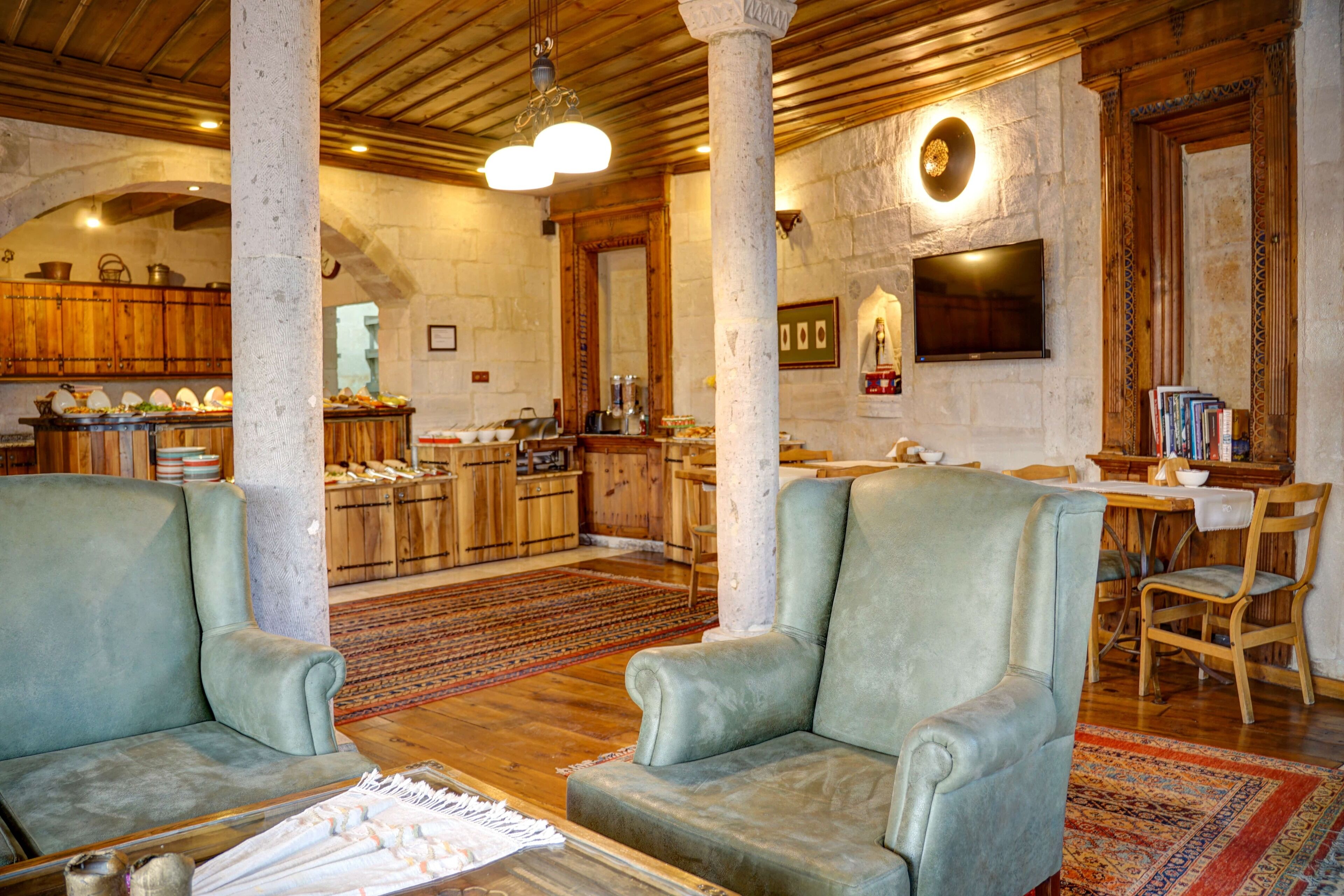 A spacious living area with two armchairs, a wooden dining table, and a kitchen in the background.