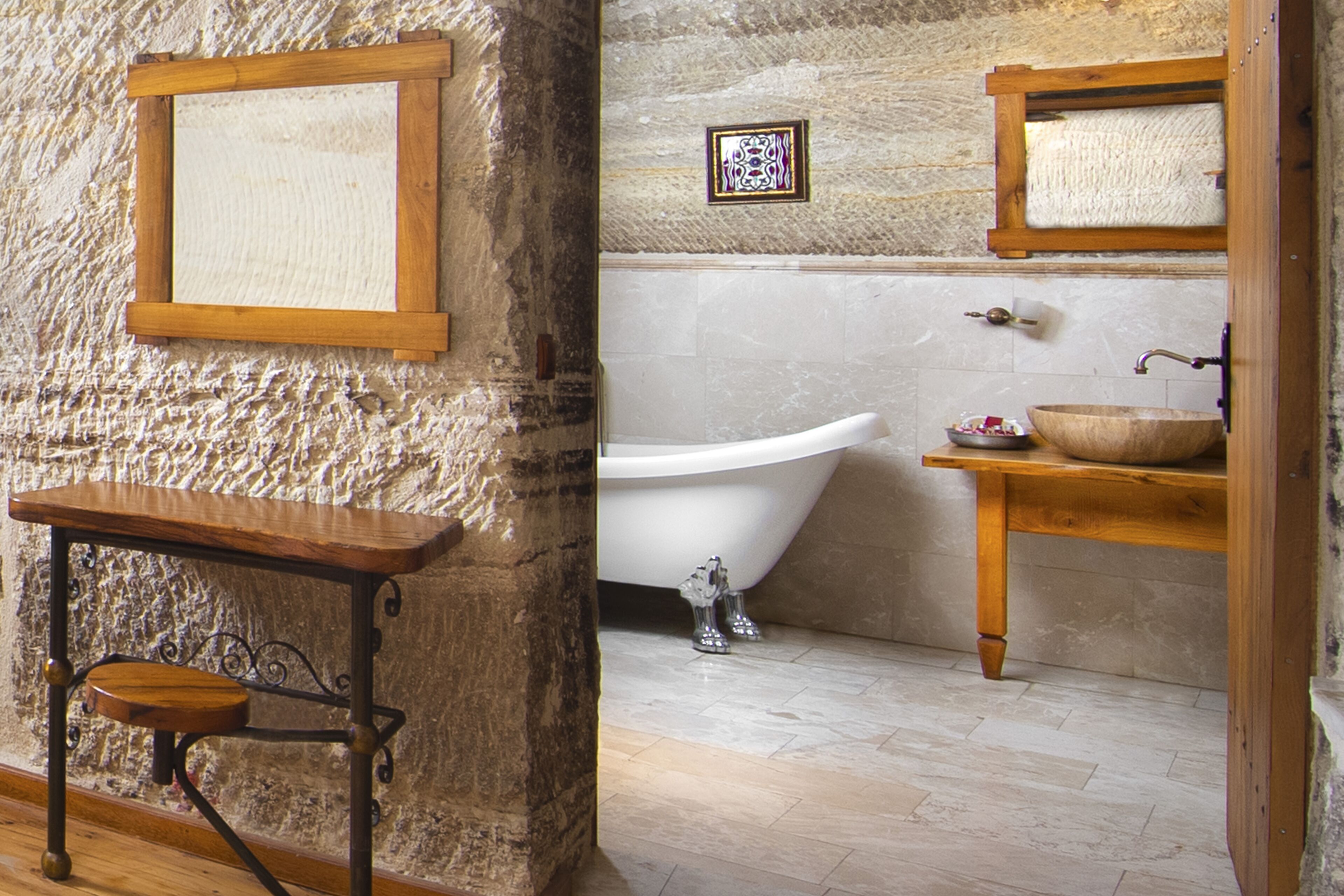 A bathroom with a wooden vanity, a freestanding bathtub, and a wooden shelf with a bowl.