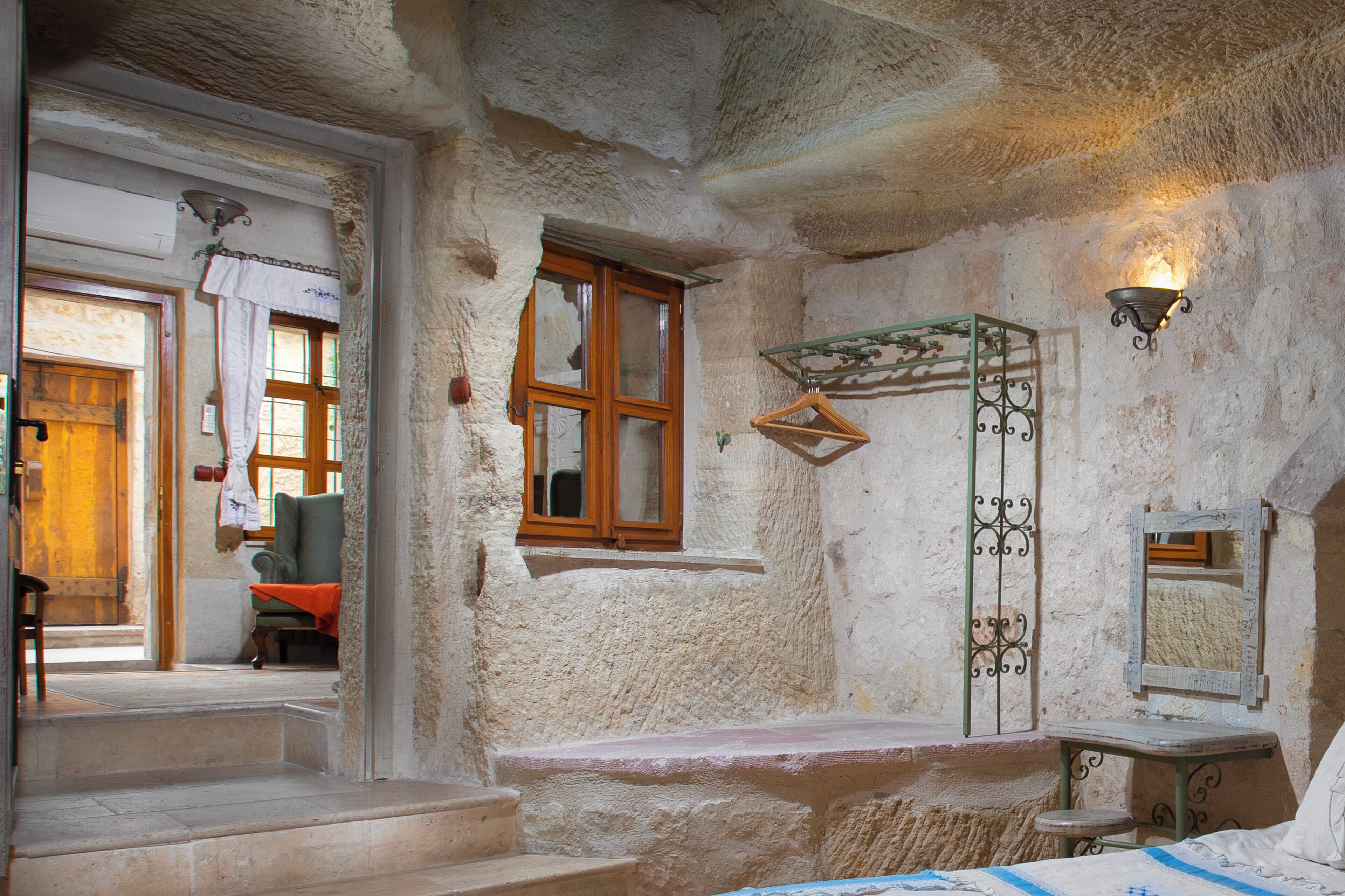 A rustic room with a stone wall, a wooden door, a bench, and a small table with a mirror.