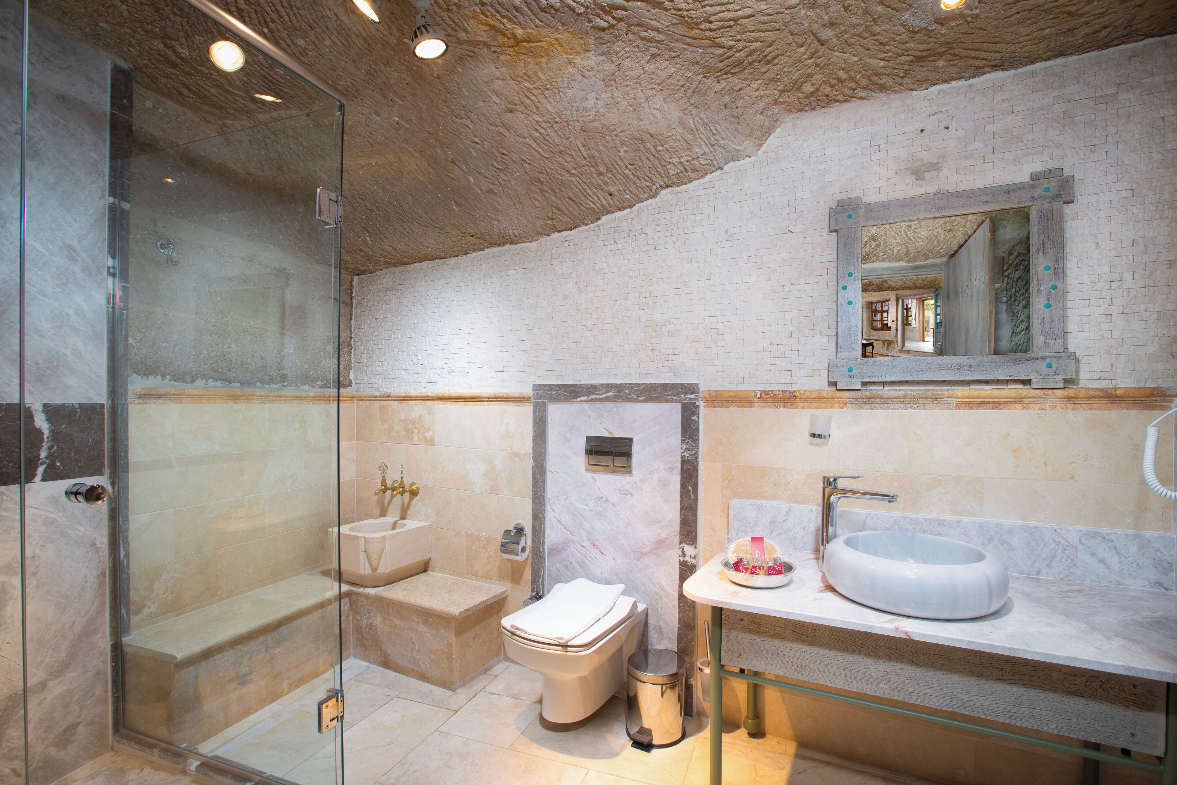 A modern bathroom with a glass shower enclosure, a marble sink, and a white toilet.