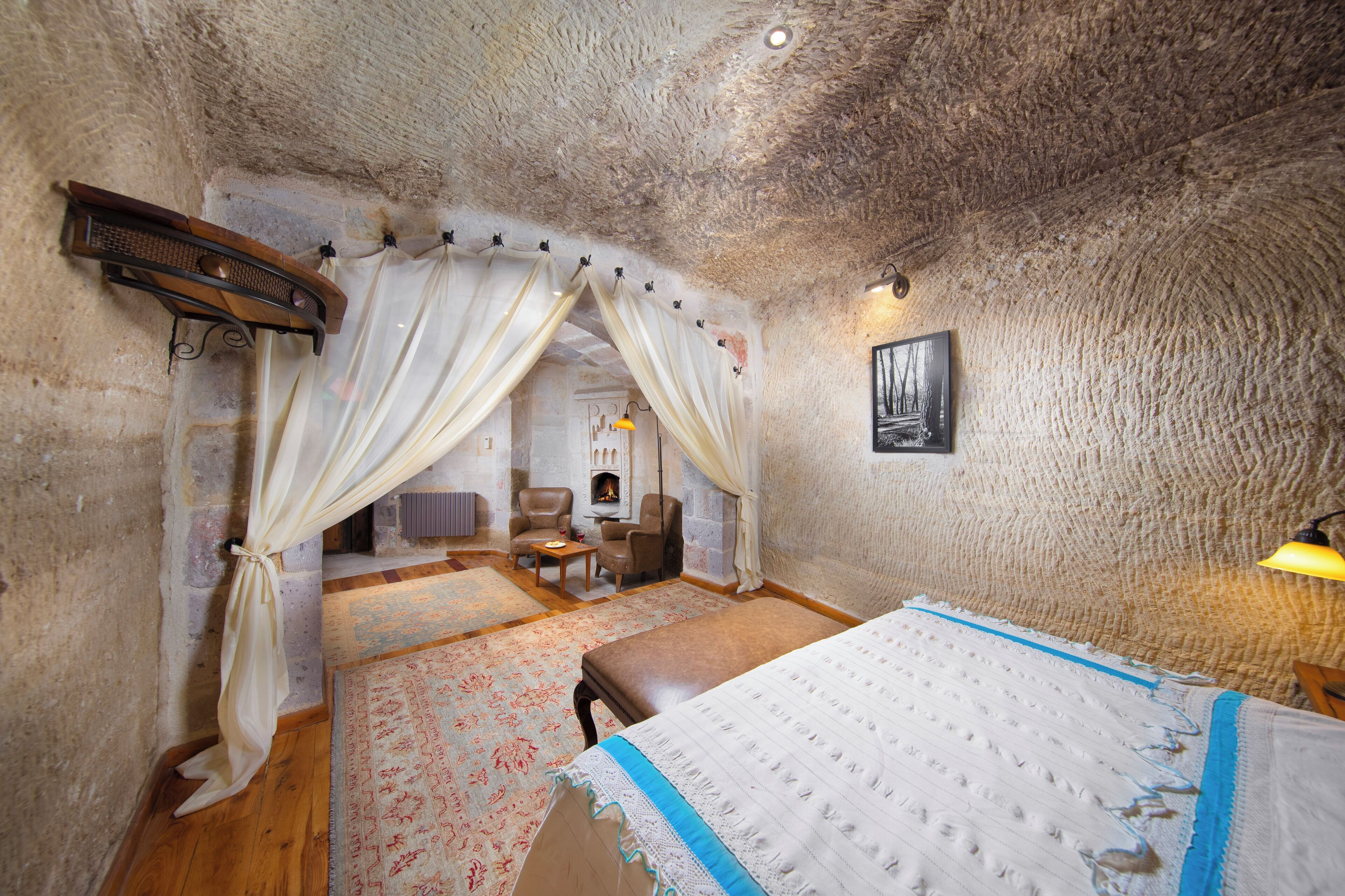 A rustic room with a bed, a fireplace, and a stone wall.