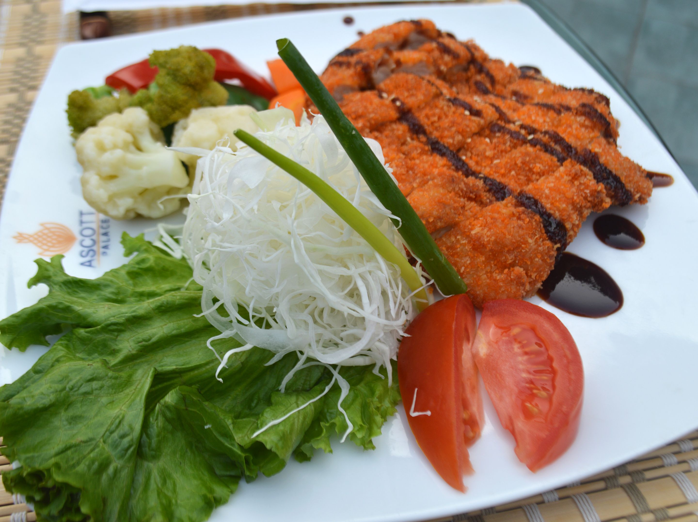Un plato de comida con pescado a la parrilla, verduras y una ensalada.