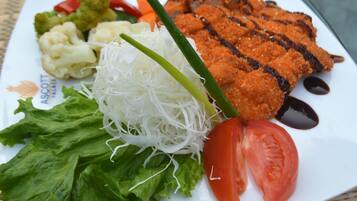 Un plato de comida con pescado a la parrilla, verduras y una ensalada.